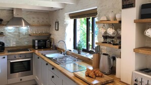 Uma cozinha moderna com eletrodomésticos de aço inoxidável, bancadas de madeira e uma janela com vista para o verde.