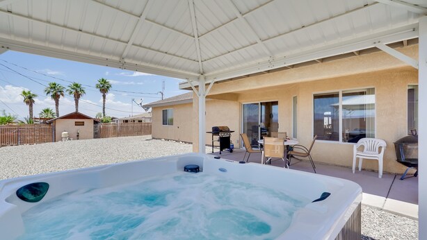 Ein Whirlpool unter einer überdachten Terrasse, im Hintergrund ein Haus.