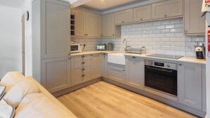 A compact kitchen with grey cabinets, a microwave, a toaster, a sink, and a dishwasher. - 2 bedroom accommodation in Fowey (Fowey)