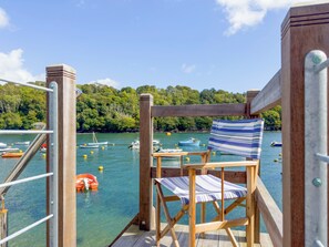 A wooden deck with a striped chair and a view of boats on calm water. - 2 bedroom accommodation in Fowey (Fowey)