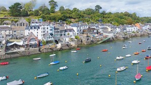 A coastal town with numerous boats docked along the waterfront, surrounded by historic buildings and a hilly backdrop. - 2 bedroom accommodation in Fowey (Fowey)