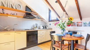 Une cuisine avec des meubles de rangement en bois, une cuisinière et un coin repas comprenant une table et des chaises.