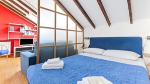 Une chambre à coucher avec un grand lit, une télévision, une bibliothèque et une fenêtre donnant sur un beau paysage.
