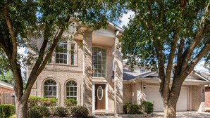 A two-story house with a brick facade, a front porch, and a garage. - North East Luxury Retreat (Round Rock)