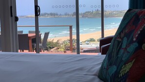 Ein Hotelzimmer mit großem Fenster mit Blick auf Strand und Meer.