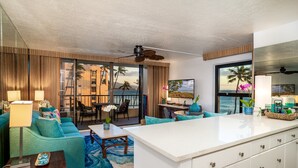 Un salon moderne doté d’un grand îlot central, d’un canapé turquoise et offrant une vue sur l’océan.