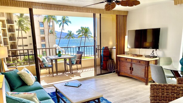 Une chambre avec un balcon, une télévision, une table à manger et un canapé.