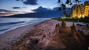 Une plage avec un château de sable et des palmiers.