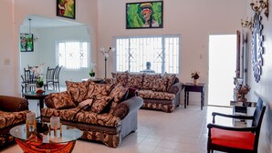 Un salon spacieux avec deux canapés à motifs, une table basse en verre et un coin repas comprenant une table et des chaises.