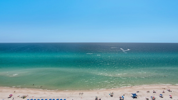 A beach with clear turquoise water, a sandy shore, and several umbrellas. - 🌊Gulf Front Master-2BR Majestic Beach Towers 2-1708🌊 (Panama City Beach)