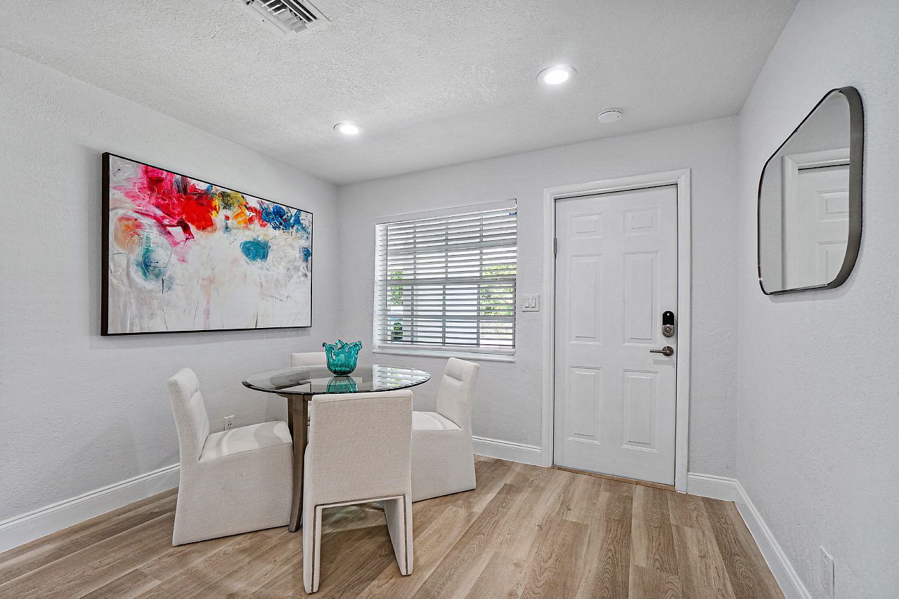 A modern interior with a dining area, a white door, and a large abstract painting.