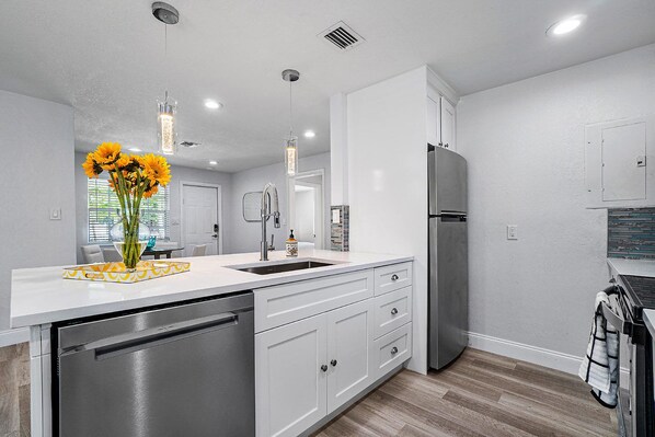 Una cocina moderna con muebles blancos, electrodomésticos de acero inoxidable y una isla central.