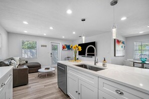 Una cocina moderna con una isla grande, electrodomésticos integrados y un comedor con mesa redonda.