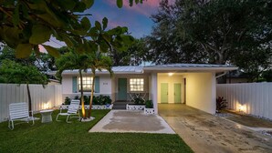 A modern house with a well-maintained lawn, a patio with chairs, and a small table.