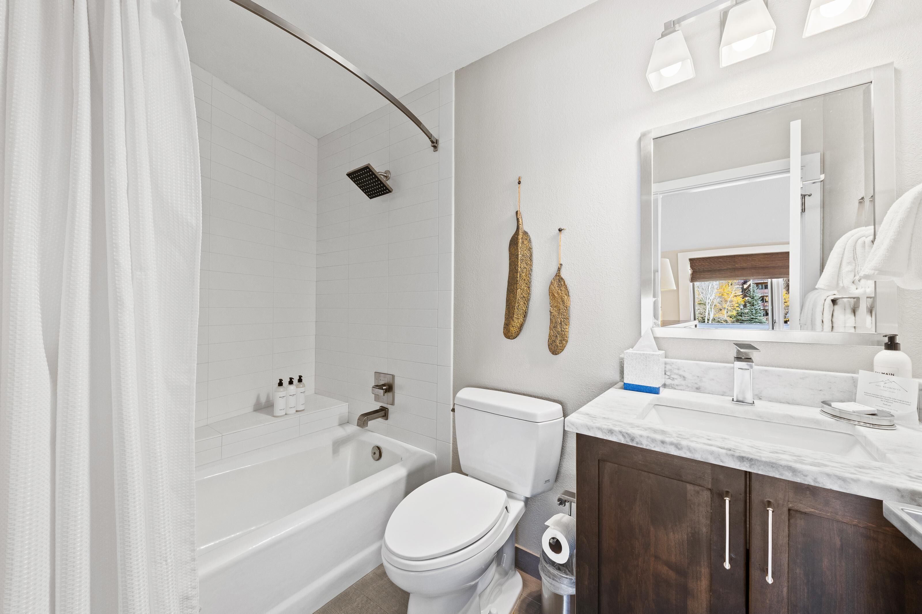 A modern bathroom with a bathtub, toilet, and vanity.