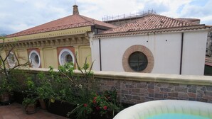 A rooftop with a swimming pool, potted plants, and a building with a tiled roof and arched windows. - Beautiful terrace and peace of mind in the city centre (Palermo)