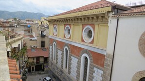 A narrow street with parked cars and buildings featuring arched windows and a yellow facade. - Beautiful terrace and peace of mind in the city centre (Palermo)