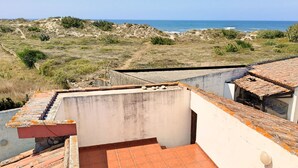 Una terrazza sul tetto con vista sul mare, caratterizzata da piastrelle in terracotta e un muro bianco.