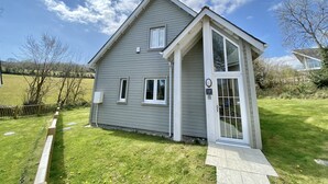 Een gelijkvloers huis met een grijze gevel en witte details, een voortuin en een kleine aangebouwde garage.