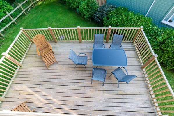 A wooden deck with a table and chairs, surrounded by a wooden fence.