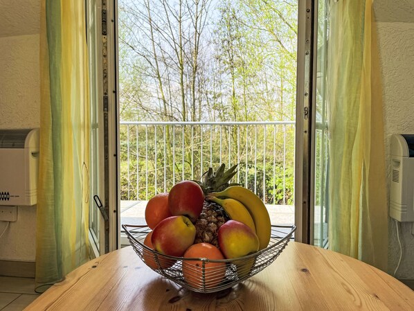 A wooden table with a fruit basket containing apples, oranges, and bananas.