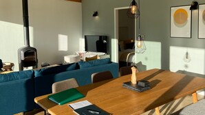 Een moderne woonkamer met een houten eettafel, een blauwe bank en een keuken op de achtergrond.
