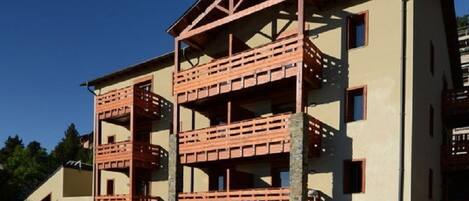 A multi-story building with a central atrium, balconies, and a stone base.