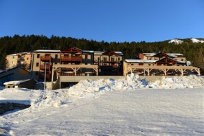 A multi-story lodge with balconies and a ski slope in the background.