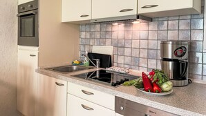 A kitchen with white cabinets, a stainless steel range hood, a coffee maker, and a sink with a faucet. - Gollwitzer Park (Insel Poel) by Interhome (Gollwitz (Insel Poel))