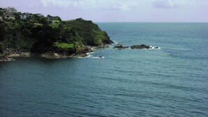 A coastal landscape with a cliff overlooking the sea, featuring houses on the hillside. - St Catherines Court No 7 (Fowey)