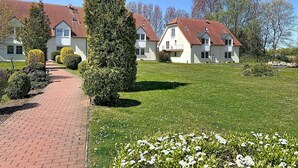 Une rangée de maisons blanches aux toits rouges, un chemin pavé et une pelouse bien entretenue.