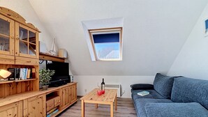 Un salon chaleureux avec un meuble en bois, un téléviseur, une petite table et un canapé bleu.
