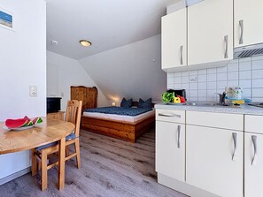 Ein kleines Zimmer mit Bett, Esstisch und Küchenzeile.