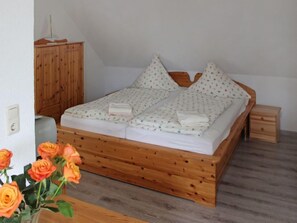 Cozy retreat with a comfortable bed, nightstand, and wardrobe, set against a simple white backdrop.