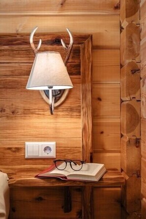 Un mur en bois avec une lampe, un interrupteur et un livre, le tout posé sur une surface en bois, avec des lunettes à côté.
