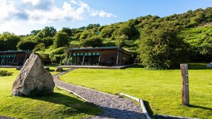 A modern building with a curved roof, surrounded by lush greenery and a clear sky. - A yorkshire dale that sleeps 6 guests  in 3 bedrooms (Richmond)