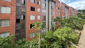 A multi-story residential building with a brick facade, multiple balconies, and a well-maintained garden area.