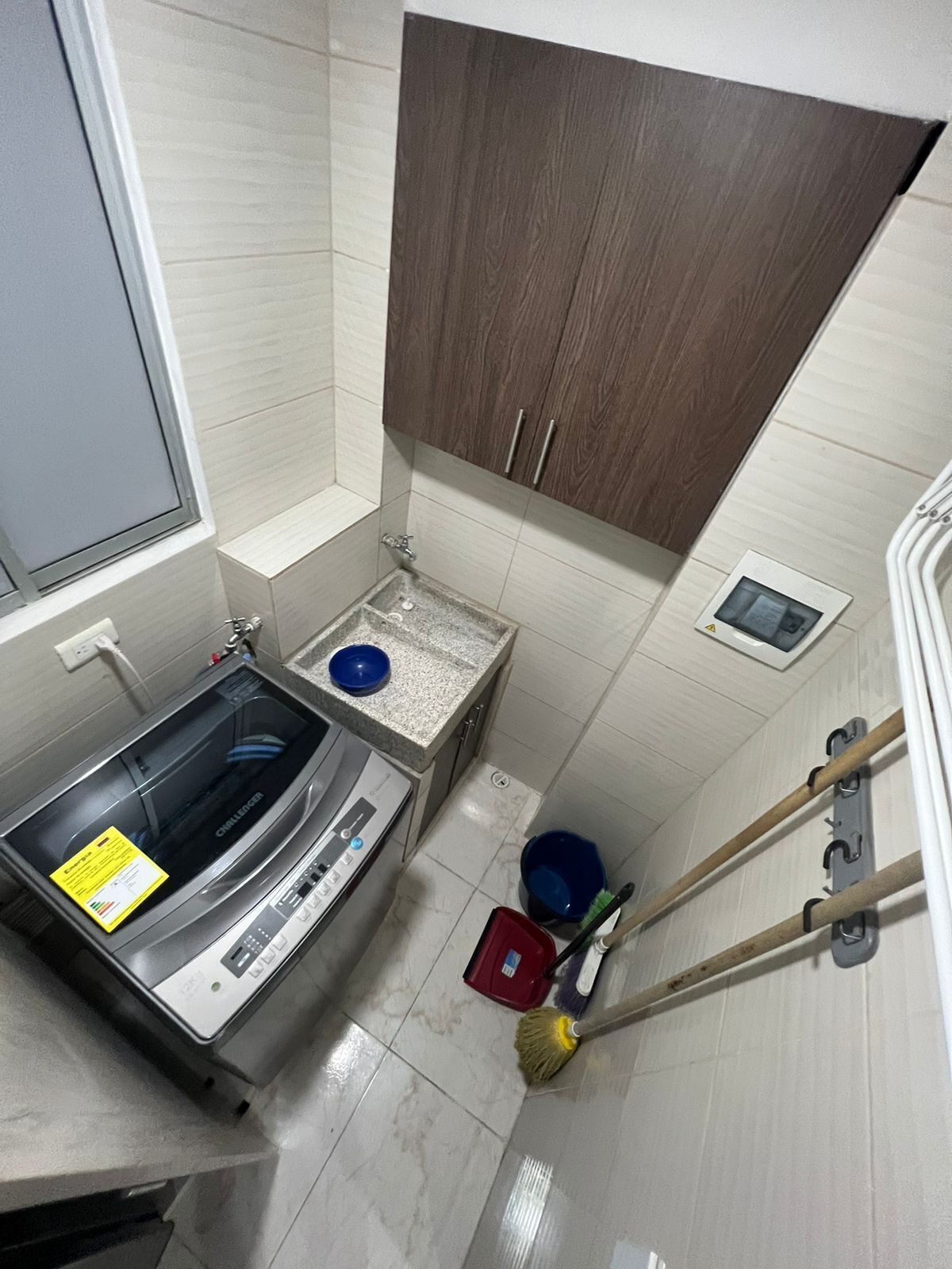 Une salle de bain compacte équipée d’un lave-linge intégré, d’un petit lavabo et de toilettes.