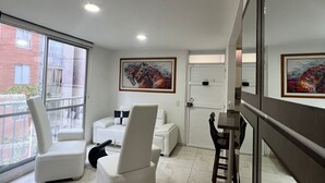 A modern living room with a sofa, chairs, a dining table, and artwork on the walls.