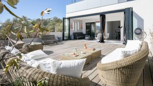 A modern outdoor deck with wicker furniture, a glass door leading to an interior space, and a clear view of the surrounding landscape. - Château by Interhome (Porto Vecchio)