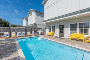 A swimming pool with lounge chairs and a wooden fence.