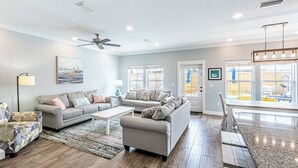 Ein geräumiges Wohnzimmer mit grauem Sofa, einem Couchtisch und einem Essbereich mit Granitplatte.