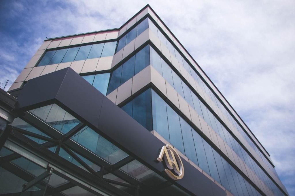 A modern building with a glass facade and a prominent logo on the corner.