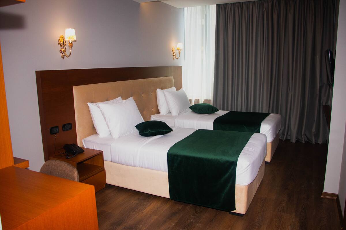 A hotel room with two beds, a desk, and a chair.