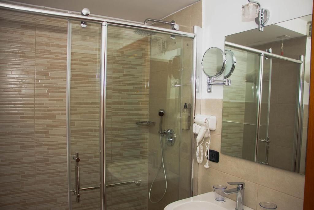 Een moderne badkamer met een douchecabine van glas, een wastafel met spiegel en een handdoekrek.