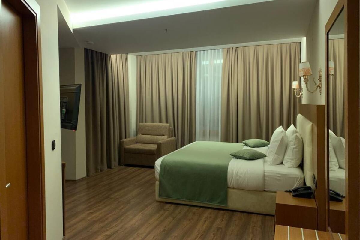 A hotel room with a bed, a chair, a TV, and a mirror.