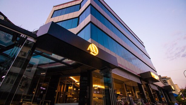 Un hotel moderno con un logotipo destacado en la fachada, amplios ventanales y una entrada en esquina.