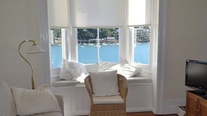 A room with a view of the sea, a wicker chair, a television, and a lamp. - 3 bedroom accommodation in Fowey (Fowey)