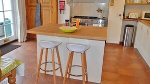A kitchen with a central island, two stools, a stove, and a microwave. - 3 bedroom accommodation in Fowey (Fowey)