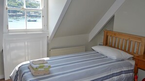 A bedroom with a bed, a window with a view of boats, and a sloped ceiling. - 3 bedroom accommodation in Fowey (Fowey)